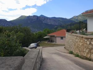 a car parked next to a stone wall with mountains at House Kona in Zupci
