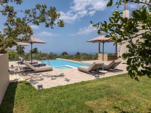 a swimming pool with lounge chairs and umbrellas at Athos Rural Villa in Prinés