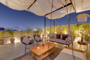 グルガオンにあるMaison Apartments by One Tree Staysのブランコとソファと椅子のあるポーチ