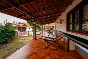 a patio with a table and benches on a house at Bhuthanakadu Retreat Homestay Chikamagalur in Mudigere