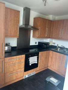 a kitchen with wooden cabinets and a stove top oven at Modern 1-Bedroom Apartment in The Hub, Milton Keynes - FREE PARKING in Milton Keynes +2 photos