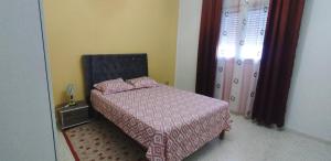 a bedroom with a bed with a pink comforter and a door at villa mimosa free parking inside in Tataouine