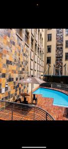 ヨハネスブルグにあるRustic Oasis at Mapungubwe 4 Star Hotel, Johannesburgのビルの隣にテーブルと傘付きのプール