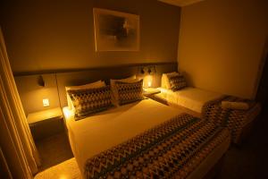 a small bedroom with two beds and two lamps at Hotel Golden Park Uberaba By Nacional Inn in Uberaba