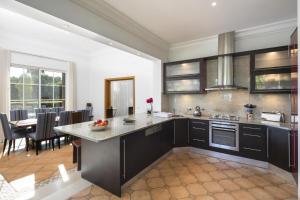 a kitchen with black cabinets and a dining room at Belinha - PINHEIROS ALTOS in Ludo