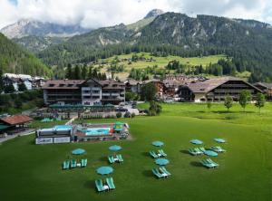 a group of lawn chairs and umbrellas on a field at Hotel Diamant Park in Campitello di Fassa