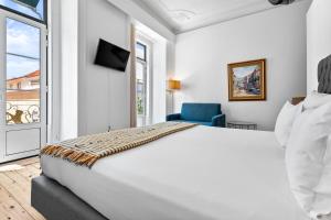 Un dormitorio con una gran cama blanca y una silla azul. en Quinta Colina by Shiadu, en Lisboa