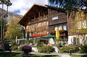 a building with umbrellas in front of it at Schweizerhaus Swiss Quality Hotel in Maloja