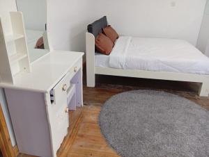 ein weißes Schlafzimmer mit einem Bett und einem Spiegel in der Unterkunft Le Tai Village Homestay in Mweiga