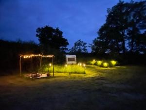 a campsite with a tent and lights at night at Camping Voi-la-la-vie in Saint-Christophe-en-Boucherie