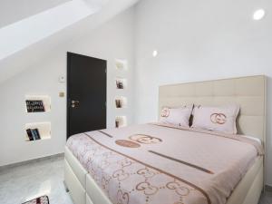 a white bedroom with a large bed with pink pillows at Holiday Home Luxury Retreat Resort by Interhome 