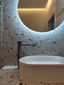a bath tub in a bathroom with a round mirror at MONACO House in Chişinău