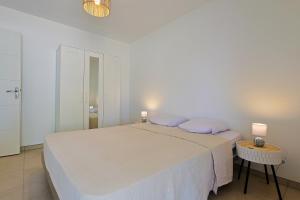 Un dormitorio blanco con una cama y una mesa. en Le Lavandou - Proche Plage, en Le Lavandou 7 fotos más