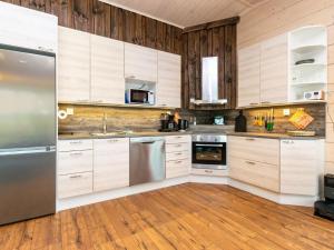 une cuisine avec des armoires en bois et des appareils en acier inoxydable dans l'établissement Holiday Home Käpälämäki by Interhome, à Putkijärvi 9 autres photos
