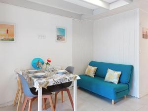 a dining room with a table and a blue couch at Holiday Home Les Charmilles-14 by Interhome in La Palmyre