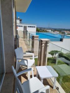 balcón con sillas, mesa y piscina en Ocean View Apartments, en Lourinhã