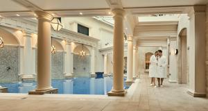 a bride and groom standing in front of a swimming pool at The Gainsborough Bath Spa - Small Luxury Hotels of the World in Bath