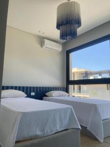 a bedroom with two beds and a large window at Almaza Bay in Alexandria