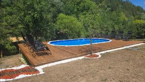a wooden deck with a swimming pool and a tree at Lion Cottage in Chuprene