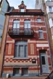 a tall red brick building with a balcony at B&B Villa Des Raisins in Bruges