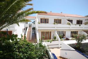 a large white house with a palm tree at Apartamento de 2 Dormitorios con Piscina en Costa Adeje in Costa de Adeje