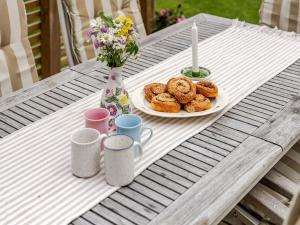 a table with a plate of donuts and cups on it at Holiday Home Torarp Västergård by Interhome in Lidhult +15 photos