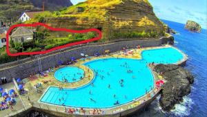 a large swimming pool with people in the water at Maresia Gardens in Porto da Cruz