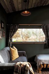 a bedroom with a couch and a large window at Holiday Home G-Wilderness Cabin by Interhome in Errogie