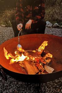 a man is cooking food in a fire pit at Holiday Home G-Wilderness Cabin by Interhome in Errogie