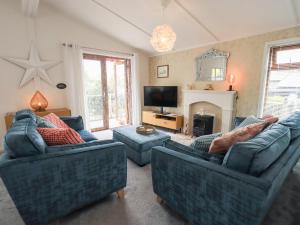 a living room with two blue couches and a fireplace at Charnwood in Carnforth