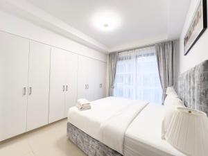 a white bedroom with a large bed and a window at 1Bedroom Apartment with Stunning Partial Sea View Pacific Al Marjan in Ras al Khaimah