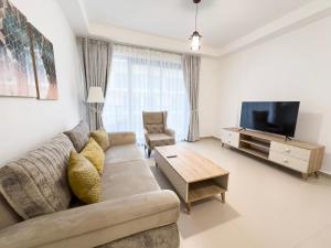a living room with a couch and a tv at 1Bedroom Apartment with Stunning Partial Sea View Pacific Al Marjan in Ras al Khaimah