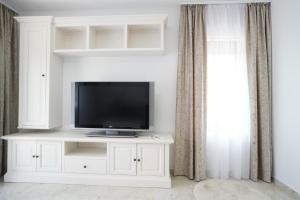 a television on a white entertainment center in a living room at Apartament Ultracentral NICOL in Curtea de Argeş