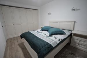 a bedroom with a bed with two blue pillows at Apartament Ultracentral NICOL in Curtea de Argeş