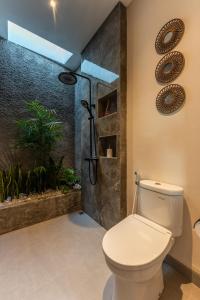 a bathroom with a toilet and an indoor shower at Villa Sattvika in Kerobokan