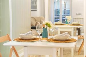 una mesa de comedor blanca con platos y copas de vino en Acogedor apartamento en el corazón de Pamplona, en Pamplona