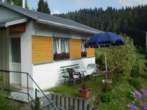 a house with a table and a blue umbrella at Heatable Pool Retreat in Neuhaus am Rennweg