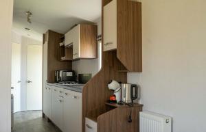 a small kitchen with wooden cabinets and a microwave at Vakantiepark de Zeeuwse Parel - Sunset in Sint Maartensdijk