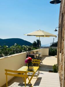a table with flowers and an umbrella on a balcony at VERANNA Patmos Studio1 in Patmos