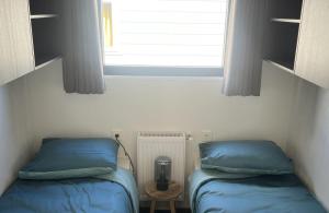 two beds in a small room with a window at Vakantiepark de Zeeuwse Parel - Zeeparel in Sint Maartensdijk