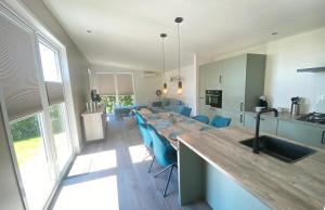 a kitchen with a long table and blue chairs at Vakantiepark de Zeeuwse Parel - de Schelde in Sint Maartensdijk