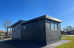 a black tiny house with a black roof at Vakantiepark de Zeeuwse Parel - De Zeester in Sint Maartensdijk