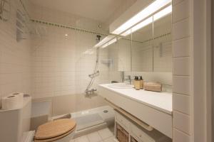 ein weißes Badezimmer mit Waschbecken und Toilette in der Unterkunft Appartement met 3 slaapkamers, terras en prachtig uitzicht in Knokke-Heist + 20 Fotos