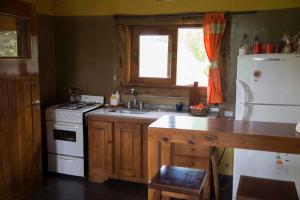 a kitchen with a white stove and a white refrigerator at Cabañas Alma de Montaña 
