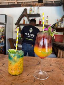 two cocktails sitting on a wooden table in a bar at Tribe Bungalows, Bwejuu, Zanzibar in Bwejuu +47 photos