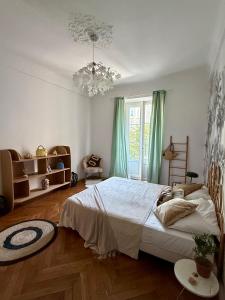 a bedroom with a large bed and a chandelier at Appartement niçois au coeur du triangle d'or in Nice
