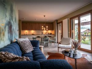 a living room with a blue couch and a kitchen at Lodge Sami - OVO Network in Samoëns