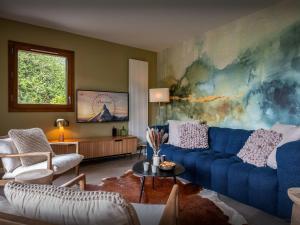 a living room with a blue couch and a painting at Lodge Sami - OVO Network in Samoëns