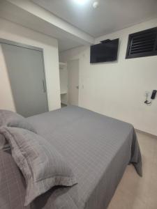 a bedroom with a bed and a television on the wall at Fortunato Hotel in Bragança Paulista