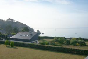 a house in a field with a fence in front of it at Le Petit Bleu I Magnifique vue mer & Plage à 50m in Crozon